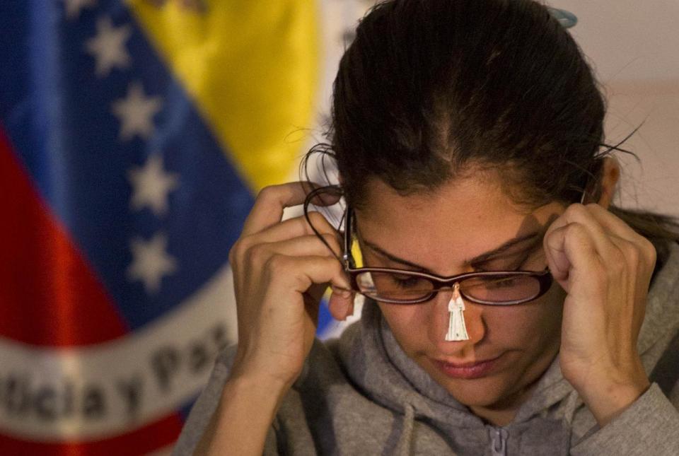 Globovision journalist Nairobi Pinto slips on a necklace decorated with an image of the Virgin Mary given to her by a colleague during a press conference following her release from a kidnapping in Caracas, Venezuela, Monday, April 14, 2014. Pinto was freed eight days after she was kidnapped in the town of Cua in Miranda state, but it's not yet clear why she was seized. (AP Photo/Ramon Espinosa)