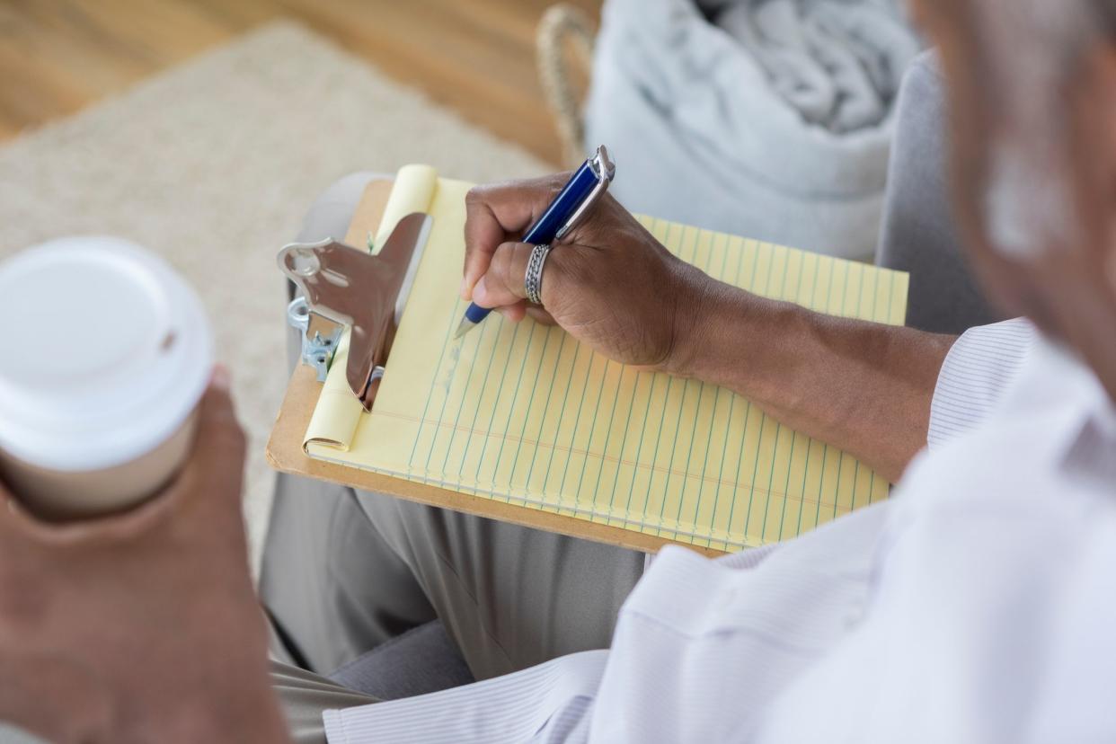 High angle view of unrecognizable African American man writing on a yellow note pad