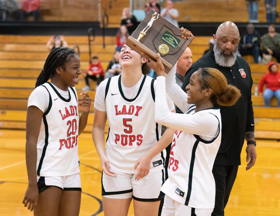 McKinley captains Arianna Snell (20), Sidnee Bowden (5), Paris Stokes (2) and head coach Bryant Bowden receive the girls Division I district championship trophy after defeating Walsh Jesuit, Friday, Feb. 24, 2023.