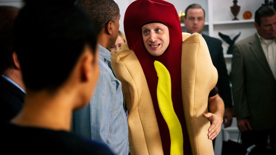 a man in a hot dog suit gesturing to a crowd