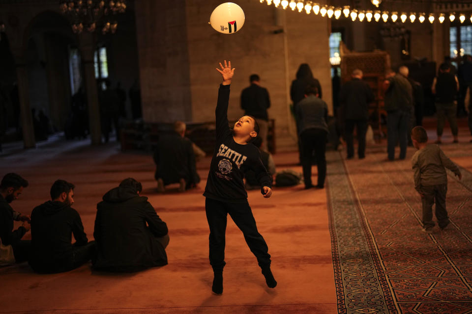 FILE - A boy plays with a ballon with a printed slogan that reads: "Palestine will be free" as Muslims worshippers pray at Sehzade mosque in Istanbul, Turkey on Nov. 12, 2023. (AP Photo/Francisco Seco, File)