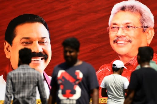 Pedestrians walk past a giant poster of Rajapaksa brothers Mahinda (left) and Gotabaya in Colombo