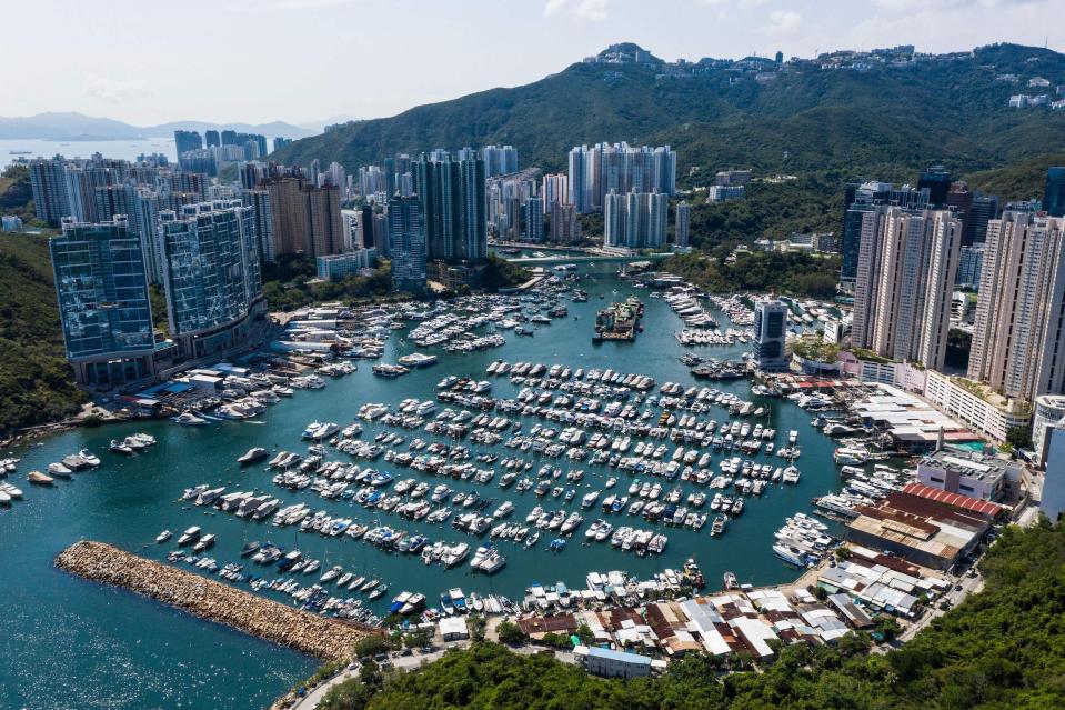 An aerial view of Aberdeen Harbor with lines of modern boats surrounded by residential and commercial buildings in Hong Kong.