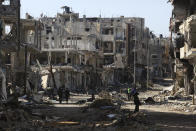 Palestinians walk through the destruction left by the Israeli offensive on Khan Younis, Gaza Strip, Friday, March 8, 2024. (AP Photo/Hatem Ali)