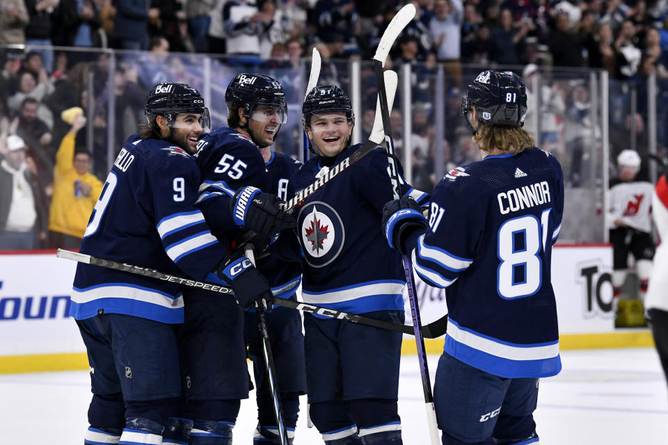 Winnipeg Jets' Cole Perfetti (91) celebrates his goal against the New Jersey Devils with Alex Iafallo (9), Mark Scheifele (55) and Kyle Connor (81) during the second period of an NHL hockey game Tuesday, Nov. 14, 2023, in Winnipeg, Manitoba. (Fred Greenslade/The Canadian Press via AP)