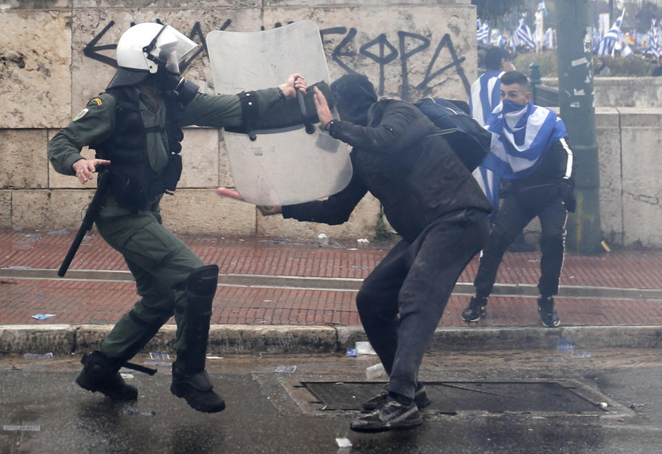 A Greek riot police fends off a demonstrator with a stick during clashes in Athens, Sunday, Jan. 20, 2019. Greece's Parliament is to vote this coming week on whether to ratify the agreement that will rename its northern neighbor North Macedonia. Macedonia has already ratified the deal, which, polls show, is opposed by a majority of Greeks. (AP Photo/Thanassis Stavrakis)