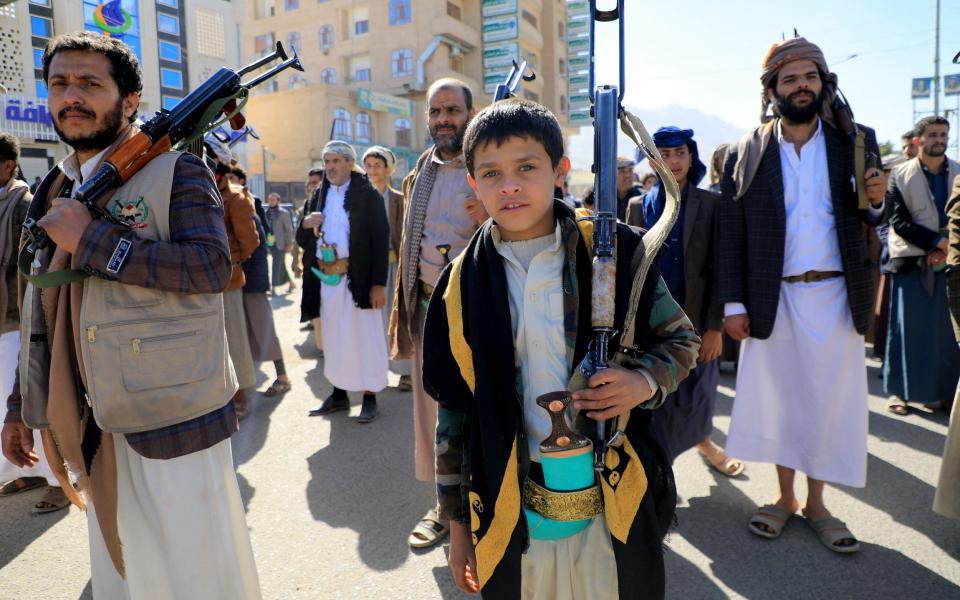 A young boy armed with a rifle marches with adult protesters in Sana'a