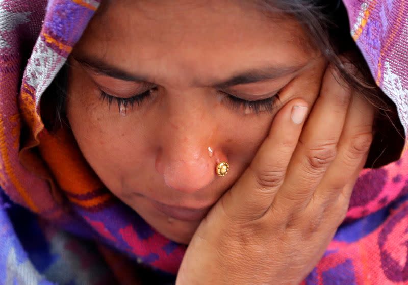 A woman weeps as she waits outside a mortuary to receive the body of her relative who died in a fire that swept through a factory where laborers were sleeping, in New Delhi