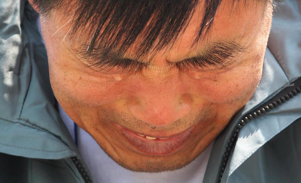 A relative of a passenger aboard the sunken ferry Sewol weeps as he waits for news on his missing loved one at a port in Jindo, South Korea, Friday, April 25, 2014. Frustrated relatives of the scores of people still missing from the sinking of the ferry Sewol staged a marathon confrontation with the fisheries minister and the coast guard chief, surrounding the senior officials in a standoff that lasted overnight and into Friday morning as they vented their rage at the pace of search efforts. (AP Photo/Ahn Young-joon)