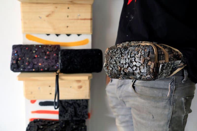 Visual artist Adeyemi Emmanuel samples a fanny pack he designed using pieces of wooden frames in his art studio in Lagos, Nigeria