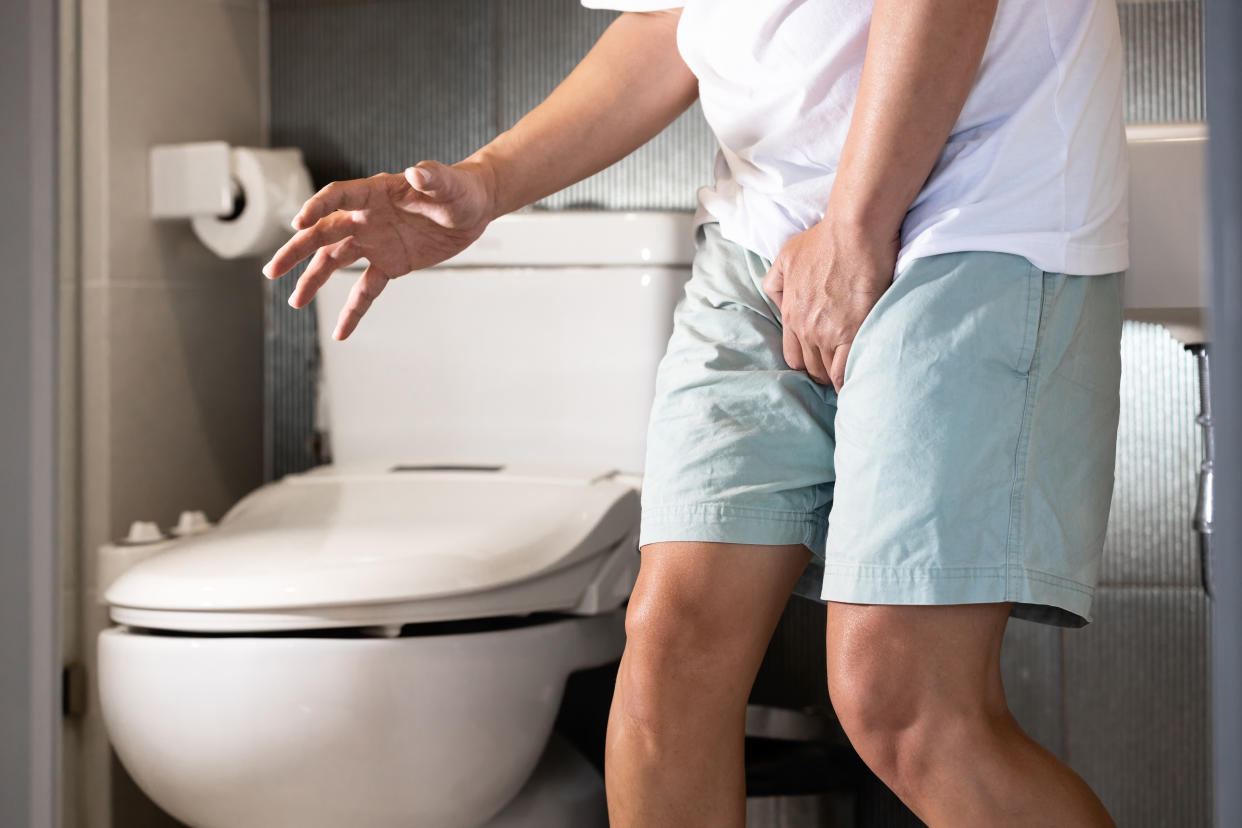 Sick asian middle aged man suffering from dysuria,acute cystitis and smelly urine from urinary tract infection,people patient holding crotch in toilet,prostate problems,painful or difficult urination