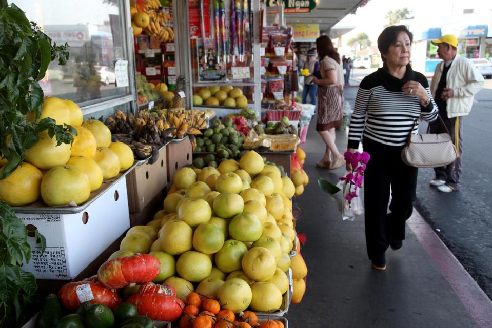 A woman carries flowers she purchased Wednesday Jan. 8, 2014 before the Tet holiday at the Bolsa Little Saigon store in Westminster, Calif. Thousands of miles from their homeland and generations on, Vietnamese-Americans celebrate Lunar New Year with traditions passed down from ancestors. They dole out red envelopes filled with fresh minted bills to herald good fortune and visit friends and family _ despite demanding work schedules and the busy pace of life in the United States. (AP Photo/Nick Ut