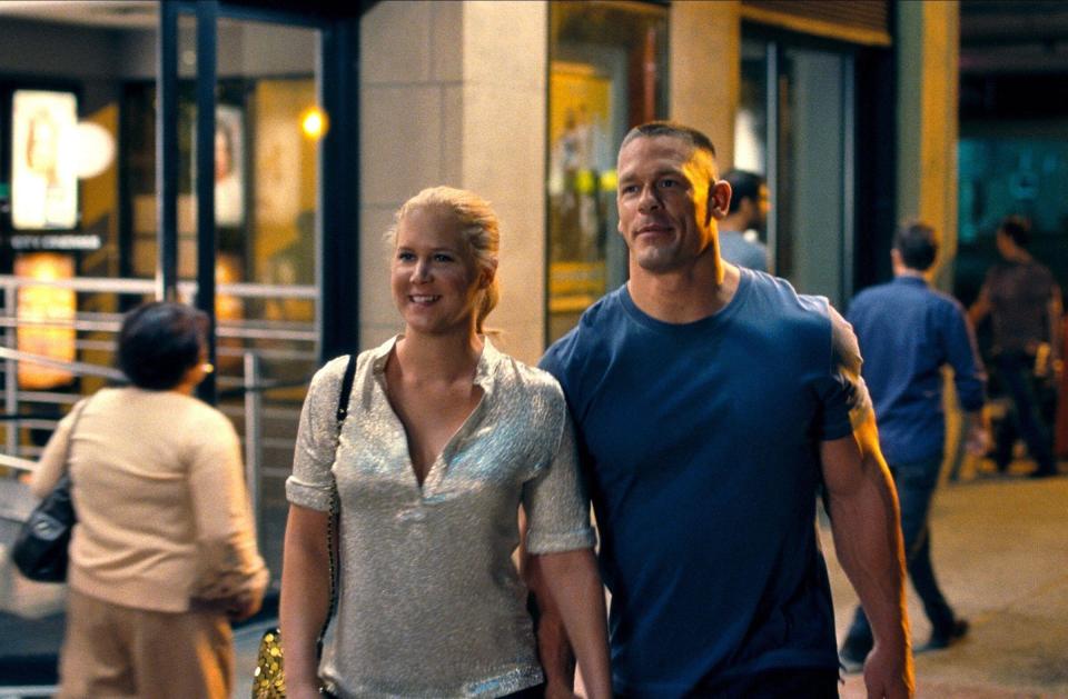 A blonde woman walks hand-in-hand with a large, muscular man in public
