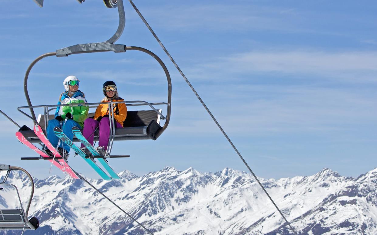 two girls in ski lift with colourful skis - Christoph Jorda /The Image Bank RF 