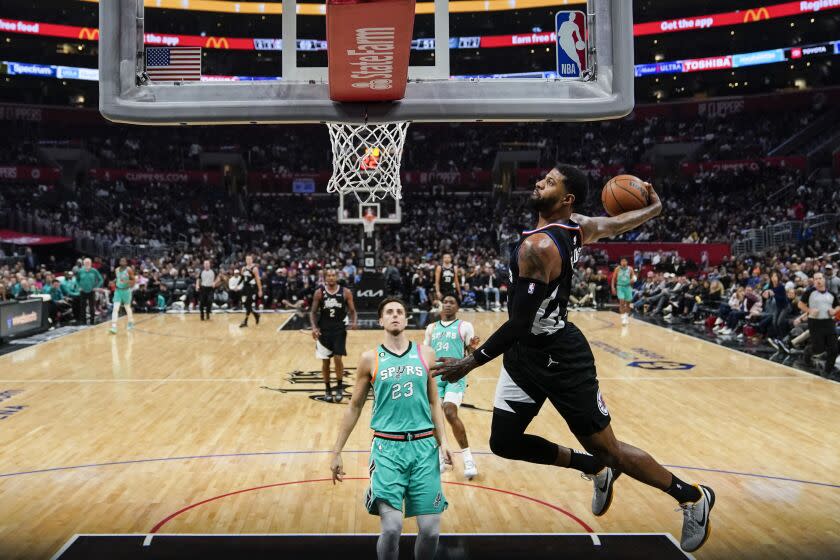 Los Angeles Clippers guard Paul George, right, makes a windmill dunk.