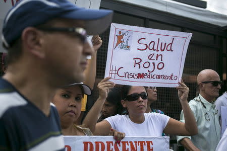 A protester holds a placard which reads "Health in red #MedicineCrisis" during a gathering in demand for medicines in Caracas, Venezuela August 27, 2015. REUTERS/Marco Bello