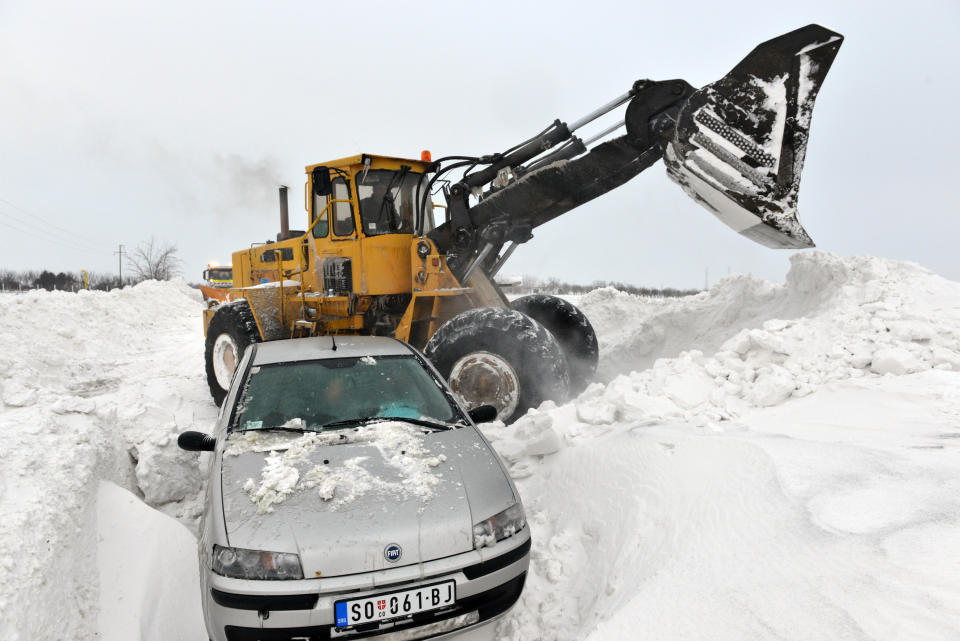 A road sweeping vehicle clears snow from the road near the city of Backa Topola, northern Serbia, Saturday, Feb. 1, 2014. Snow drifts formed by stormy winds have blocked two passenger trains and dozens of vehicles in northern Serbia, while authorities closed down several roads and a border crossing with Hungary. The state railway company says two trains to and from Hungary got stuck early on Saturday because of meters-high snow piles that formed on the railway. Emergency officials say several dozen passengers from the trains will be evacuated.(AP Photo/Darko Dozet) SERBIA OUT