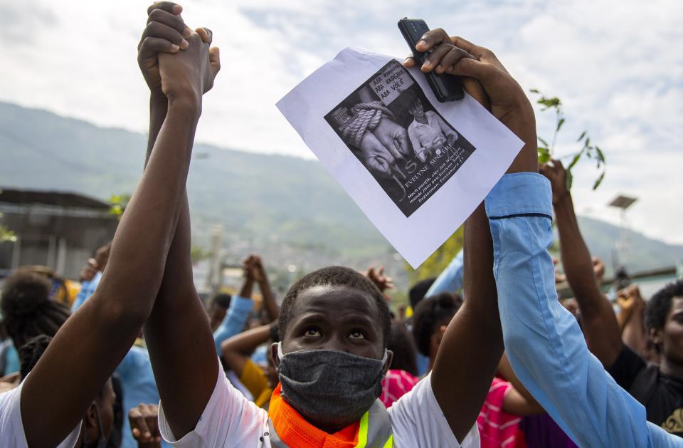 Protesters hold hands as they march to demand answers after the kidnapping and murder of high school senior Evelyne Sincère, in Port-au-Prince, Haiti, Thursday, Nov. 5, 2020. The young woman was found in a trash heap Sunday after relatives said they were unable to pay the large ransom demanded by her captors. Human rights groups contend the incident highlights the nation’s worsening security crisis. (AP Photo/Dieu Nalio Chery)