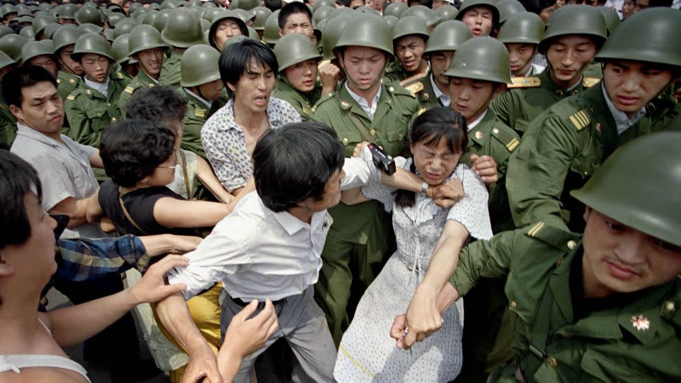 A young woman is caught between civilians and Chinese soldiers near the Great Hall of the People in Beijing, June 3, 1989. - Jeff Widener/AP