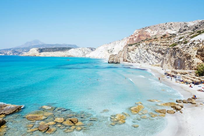 Turquoise blue water and beach surrounded by cliffs.