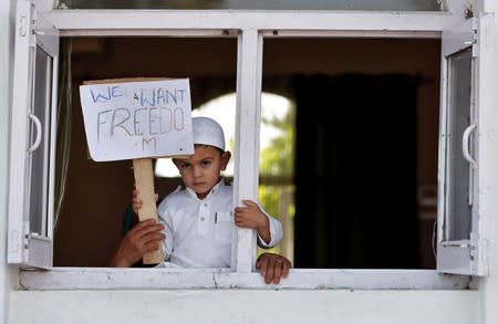 A Kashmiri boy displays a placard from a window at a protest site after Friday prayers during restrictions, after scrapping of the special constitutional status for Kashmir by the Indian government, in Srinagar