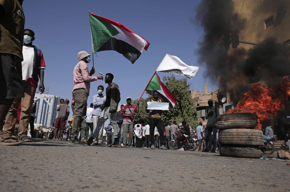 People chant slogans and burn tires during a protest to denounce the October 2021 military coup, in Khartoum, Sudan, Tuesday, Jan. 4, 2022. Sudanese took to the streets in the capital, Khartoum, and other cities on Tuesday in anti-coup protests as the country plunged further into turmoil following the resignation of the prime minister earlier this week. (AP Photo/Marwan Ali)