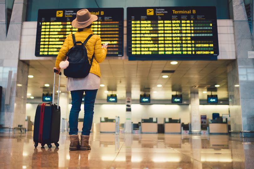 Young woman at the airport in Barcelona checking for the flight schedule