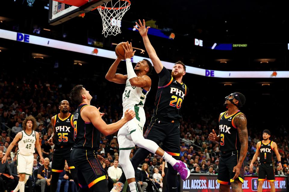 Bucks forward Giannis Antetokounmpo goes up for a shot between Suns center Jusuf Nurkic (20) and guard Grayson Allen during the first quarter Tuesday.