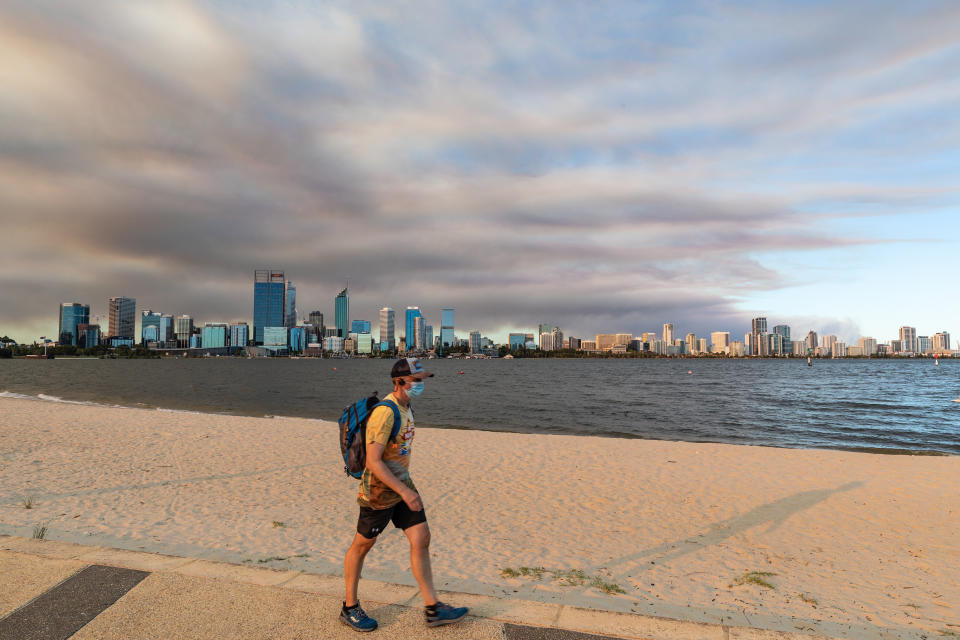 Members of the public exercise on the south Perth foreshore as smoke caused by a bushfire in the Perth hills suburb of Wooroloo rises above the city skyline in Perth.