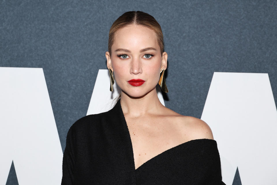 Jennifer Lawrence appears on the red carpet in an off-shoulder black dress and gold earrings at a celebrity event