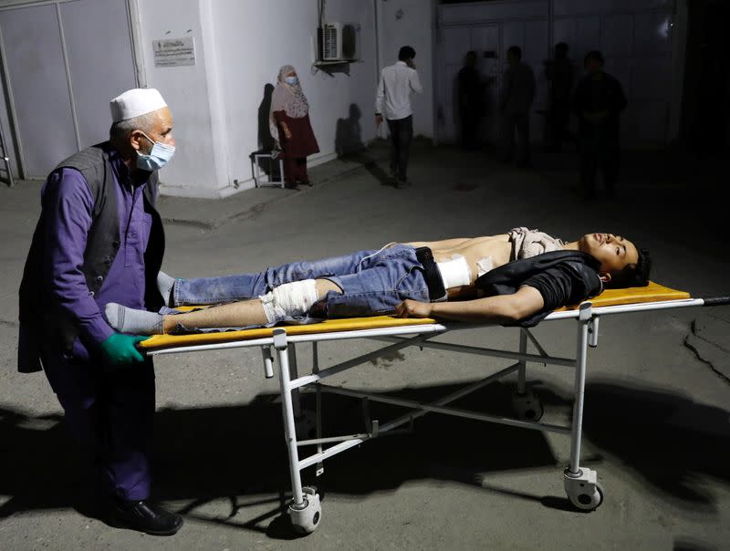 An Afghan man wheels an injured man in a hospital after a suicide bombing in Kabul