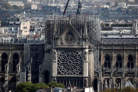 A view shows a damaged section of Notre-Dame Cathedral two days after a massive fire devastated large parts of the gothic structure as a French flag on top of the Paris town hall is seen in the backgroud in Paris, France, April 17, 2019. REUTERS/Benoit Tessier