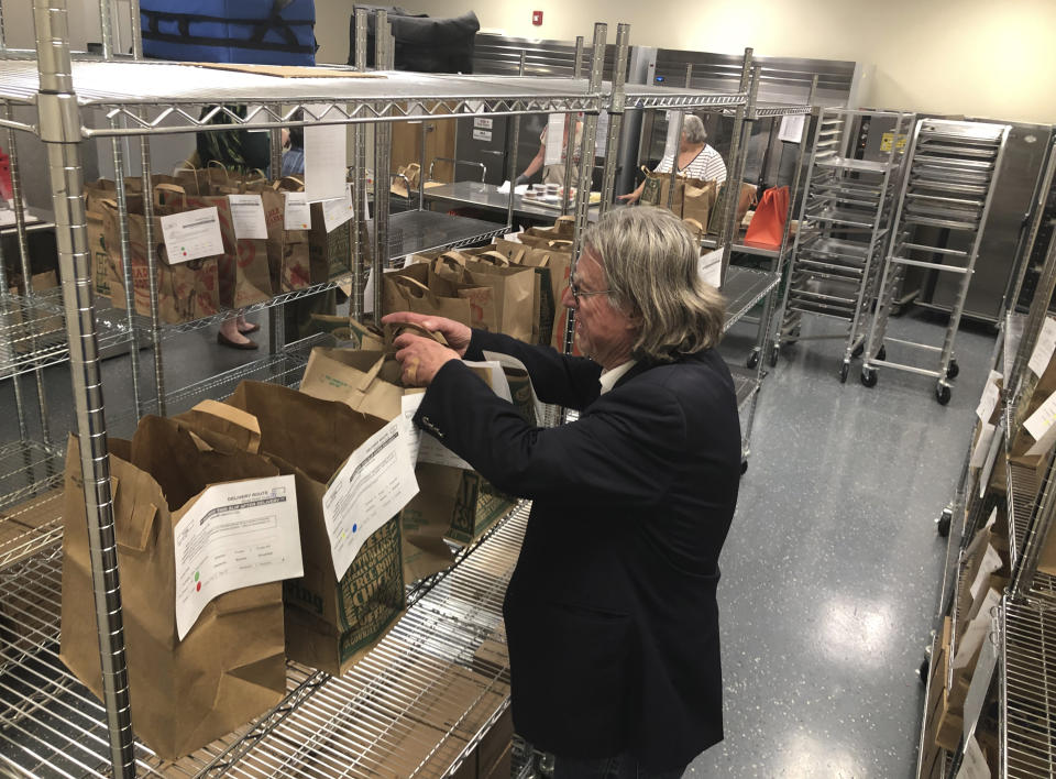 In this photo taken Friday, June 14, 2019, volunteers including 67-year-old consultant John Miller pick up food packages to deliver to homebound families and dependent children in Santa Fe, N.M., at the headquarters for Kitchen Angels. An annual report on childhood well-being from the Annie E. Casey Foundation ranks New Mexico last among 50 states that includes measures of poverty, health care, education and family support. The number of children living in poverty has swelled over the past three decades in fast-growing, ethnically diverse states such as Texas, Arizona and Nevada as the nation's population center shifts south and west. (AP Photo/Morgan Lee)