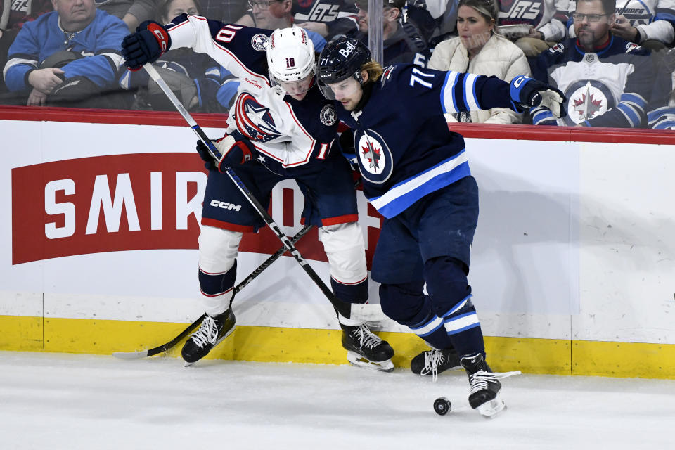 Columbus Blue Jackets' Dmitri Voronkov (10) and Winnipeg Jets' Axel Jonsson-Fjallby (71) battle for the puck during the third period of an NHL hockey game, Tuesday Jan. 9, 2024 in Winnipeg, Manitoba.(Fred Greenslade/The Canadian Press via AP)