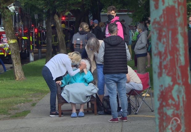 Family and neighbours comfort an elderly woman following a fire in her apartment in Vancouver's West End on Thursday. (Maggie MacPherson/CBC - image credit)