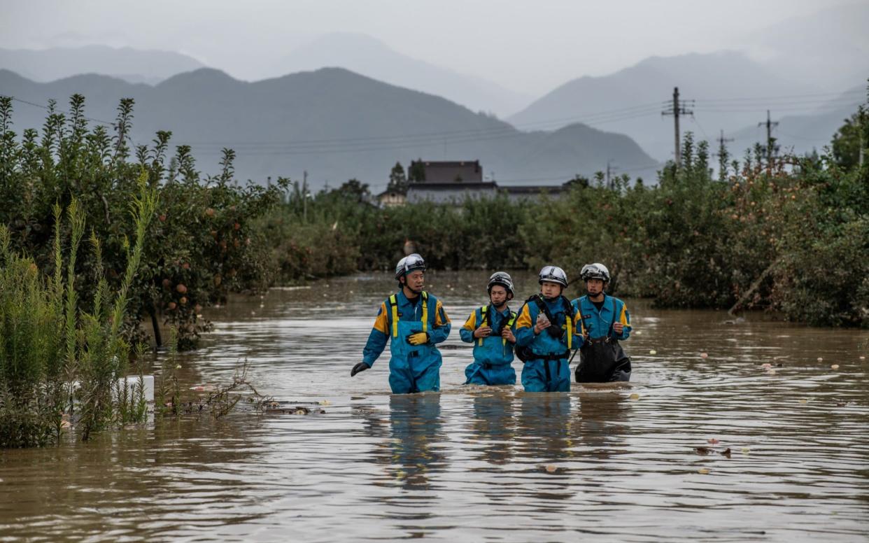 Rescue workers wade through floodwater as they search an area affected by Typhoon Hagibis - Getty Images AsiaPac