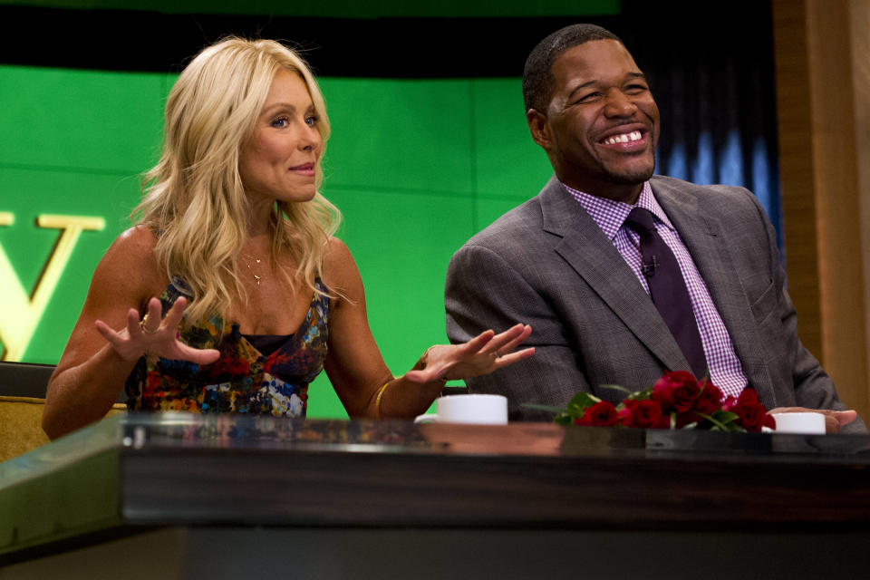 Former football player Michael Strahan, right, sits with Kelly Ripa on the set of the newly named "Live! with Kelly and Michael" on Tuesday, Sept. 4, 2012 in New York. Strahan joined the popular morning show as a permanent co-host on Tuesday, fulfilling a joking prophecy he made to Regis Philbin more than four years ago. The gap-toothed former New York Giant jogged onto the morning show set and picked up co-host Kelly Ripa in a bear hug, lifting her off her feet. He replaces Philbin, who left last November. Strahan was the survivor in a series of on-air tryouts of potential co-hosts since Philbin left, and his hiring has been an open secret for the past two weeks. (Photo by Charles Sykes/Invision/AP Images)