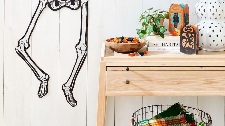 room decorated with paper skeleton on wall, bowl of candy, and paper lanterns for halloween party