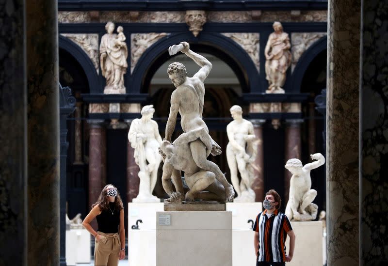 Victoria & Albert (V&A) Museum gallery assistants pose for members of the media in front of the 'Samson Slaying a Philistine' sculpture during preparations to reopen the museum, in London