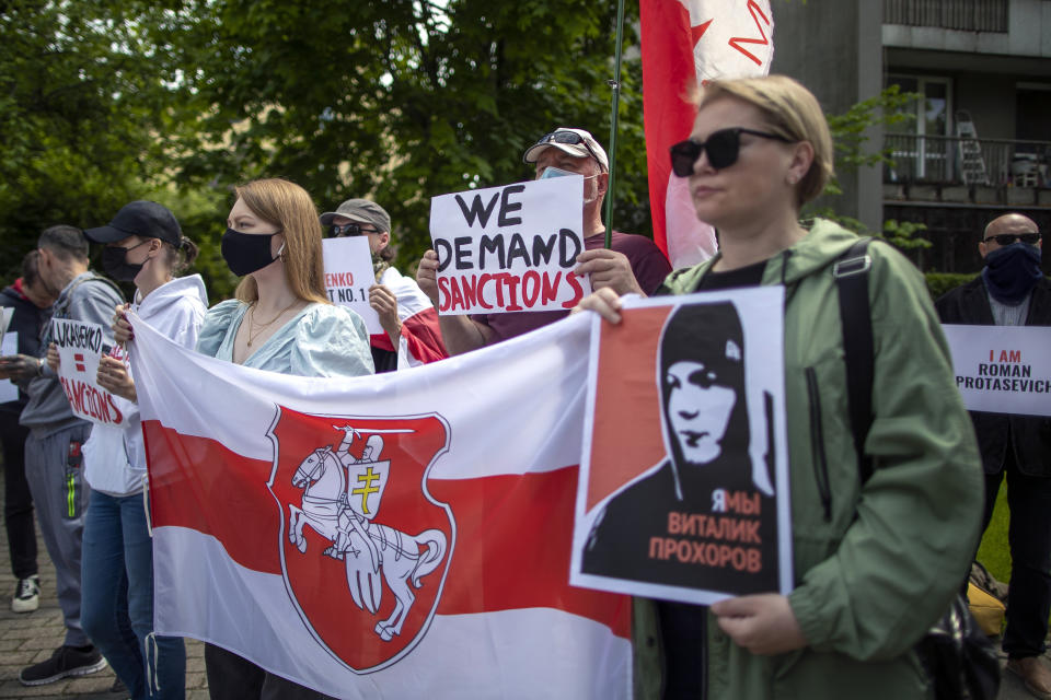 Protesters hold banners and Old Belarusian national flag during a demonstration demanding freedom for Belarus opposition activist Raman Protasevich, in front of the U.S. Embassy in Vilnius, Lithuania, Friday, May 28, 2021. European Union nations are sketching out plans for new sanctions against Belarus that will target economic sectors close to its authoritarian president, as they seek to strike back at him for the forced diversion of a passenger jet to arrest a dissident journalist. (AP Photo/Mindaugas Kulbis)