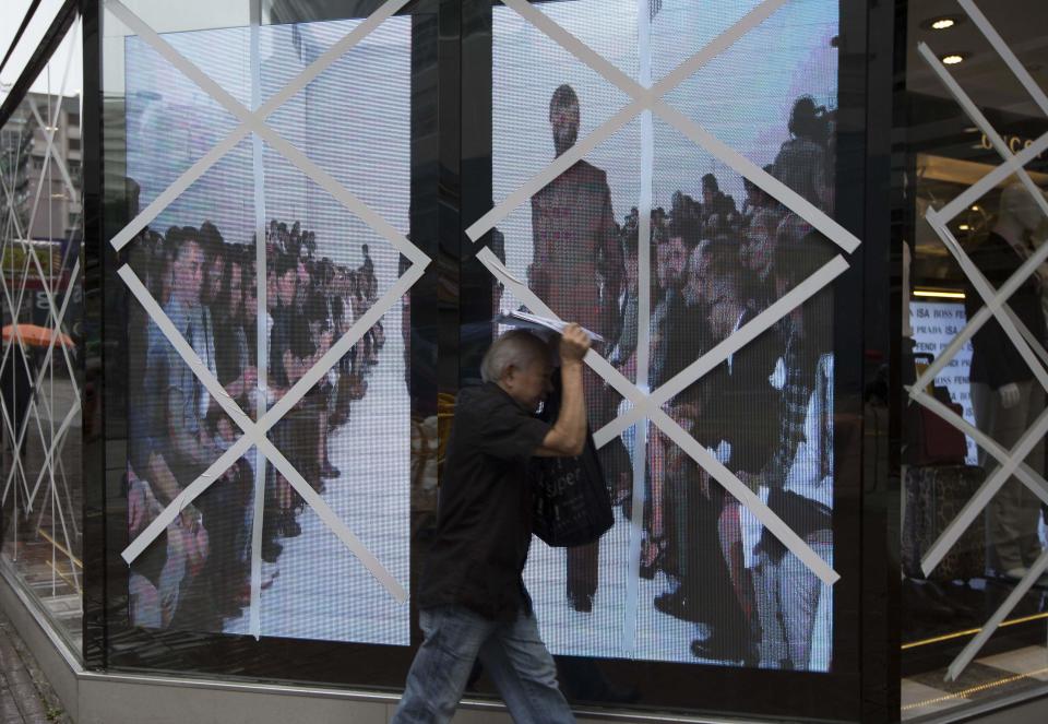 A man walks past the windows of a boutique store that have been taped-up in preparation for Typhoon Usagi at Tsim Sha Tsui shopping district in Hong Kong