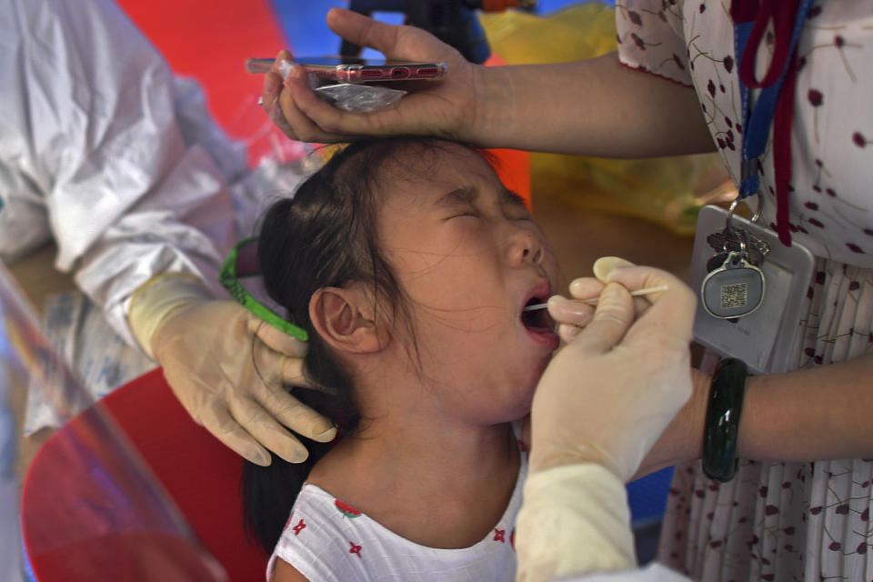 A child reacts as she gets a swab during the third-round of coronavirus test at a residential block in Wuhan city in central China's Hubei province, Wednesday, Aug. 11, 2021. The World Health Organization says it will soon test three drugs used for other diseases to see if they might help patients sickened by the coronavirus. (Chinatopix Via AP)