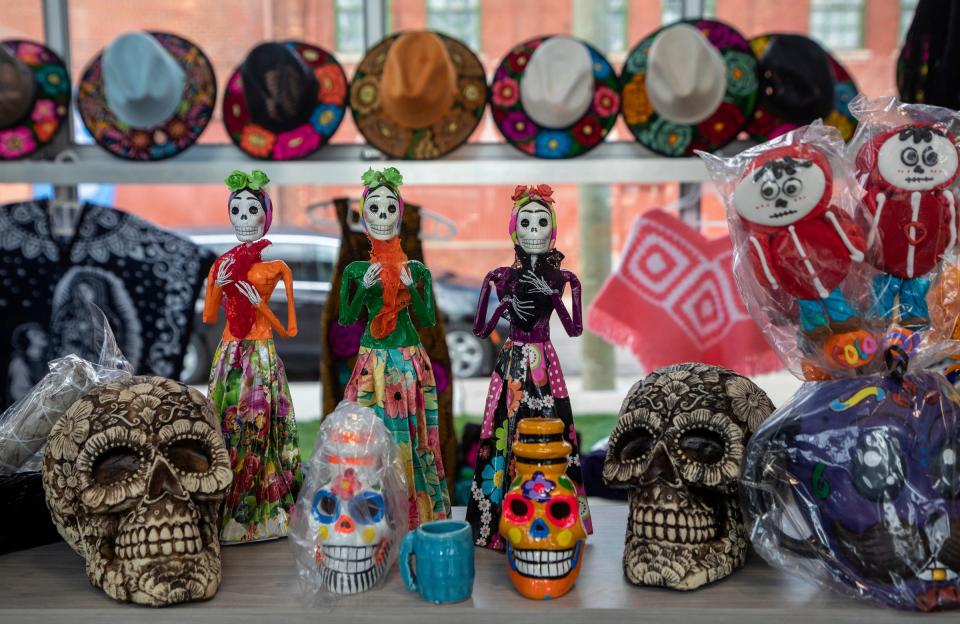Colorful skulls and clothing are displayed on a table during a Dia de los Muertos event.