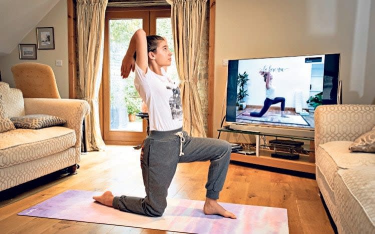 Lizzie Ward's daughter Emily, 12, takes part in her mother's yoga class via Zoom from another room at their home in Northamptonshire - Andrew Fox