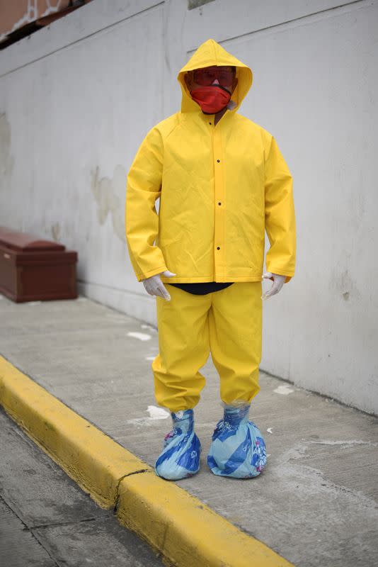 A funeral home worker in a protective suit waits outside Los Ceibos hospital after Ecuador reported new cases of coronavirus disease (COVID-19), in Guayaquil