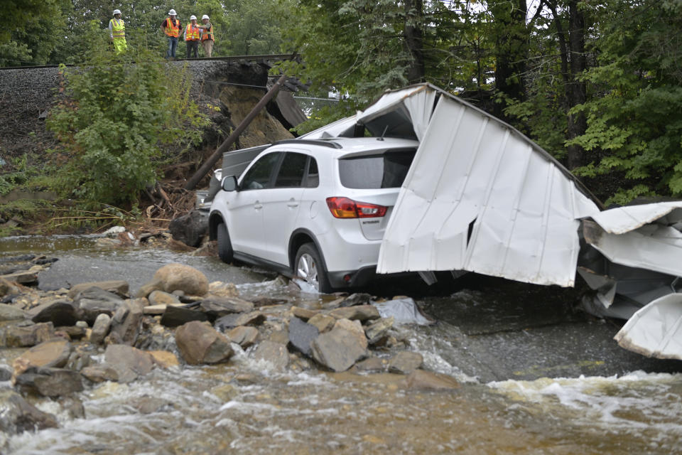 Workers survey the damage to a Commuter Rail train line which was washed out Tuesday, Sept. 12, 2023, in Leominster, Mass. after heavy rain fall in the town overnight. (AP Photo/Josh Reynolds)