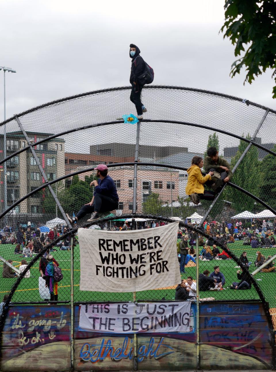 A young man stands atop a backstop in the Capitol Hill Autonomous Zone in Seattle during protests following the death of George Floyd.