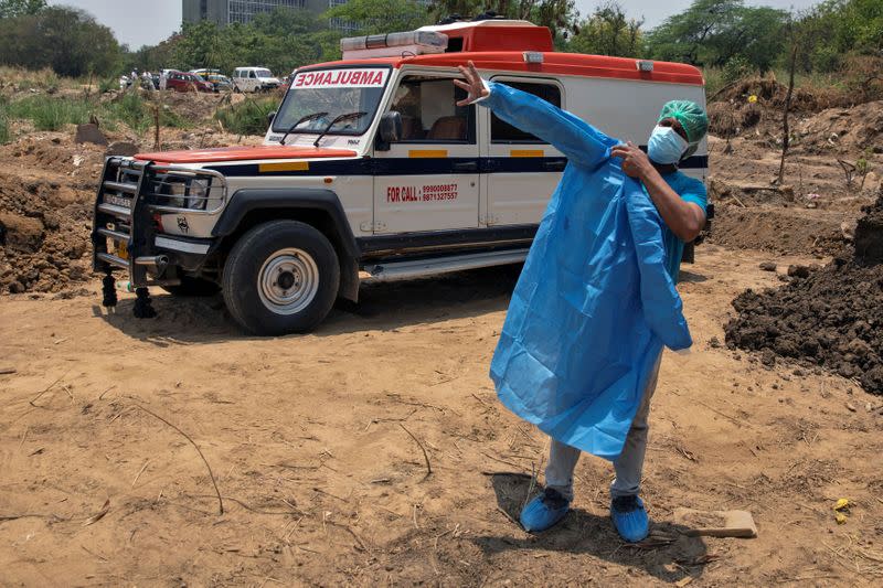 Mohammad Aamir Khan, an ambulance driver, changes his personal protective equipment (PPE) as he prepares to take out bodies of people who died due to the coronavirus disease (COVID-19), before their burial at a graveyard in New Delhi