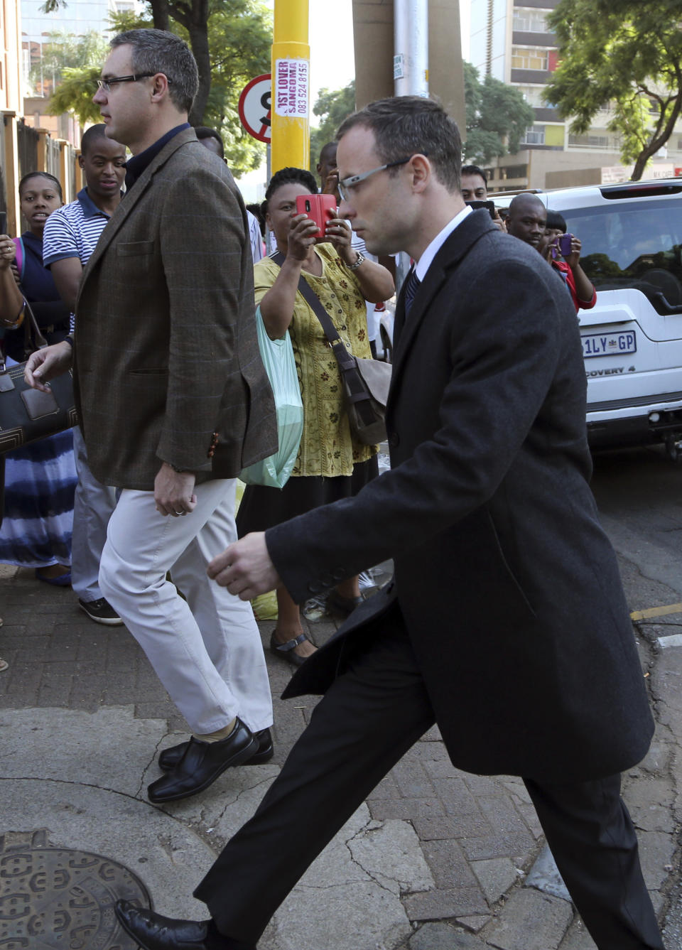 Oscar Pistorius, right, walks towards the high court in Pretoria, South Africa, Tuesday, April 8, 2014. Pistorius, who is charged with murder for the shooting death of his girlfriend, Reeva Steenkamp, on Valentines Day in 2013, was testifying for a second day at his murder trial Tuesday, answering questions from his defense lawyer. (AP Photo/Themba Hadebe)