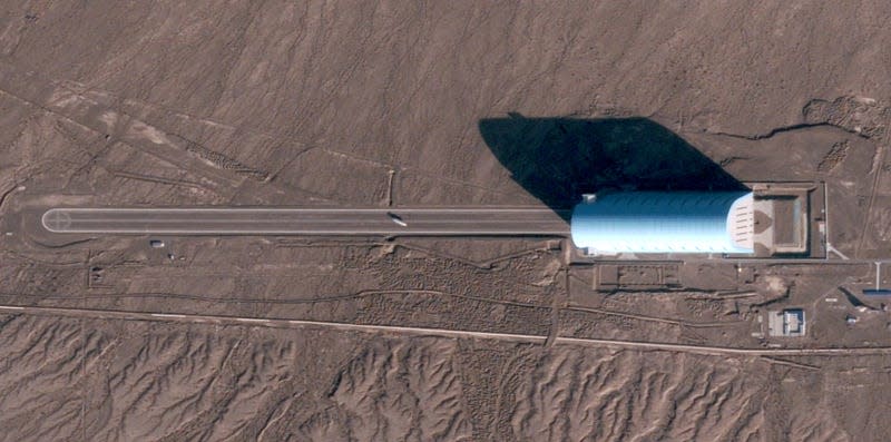 A lighter-than-air vehicle  on the tarmac outside a massive hangar in Xinjiang, China.